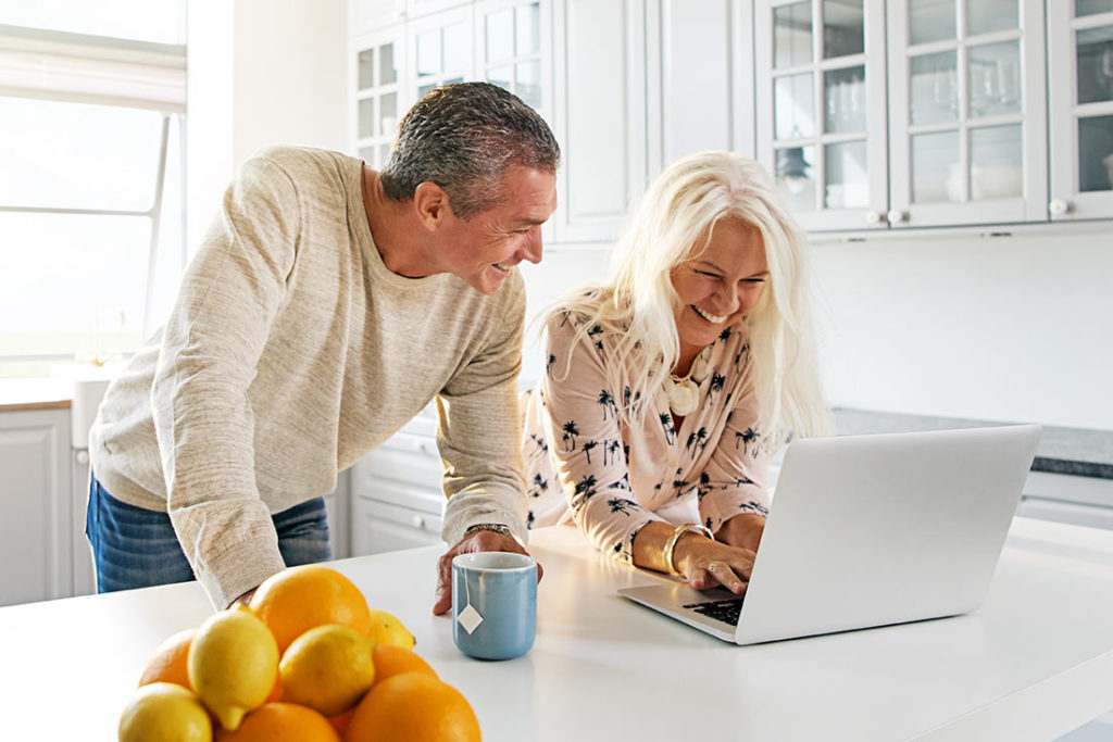 couple on laptop at their kitchen island contact financial advisor