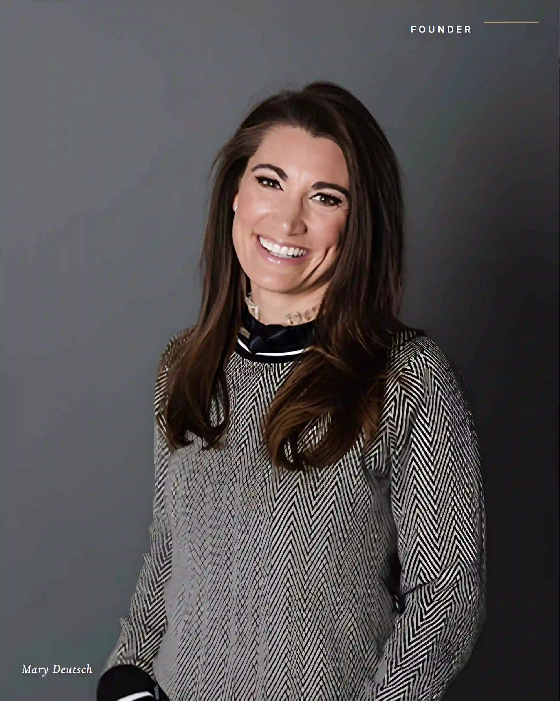 Mary Deutsch, Founder at MTD Financial, smiling in a grey patterned top with black trim against a dark background